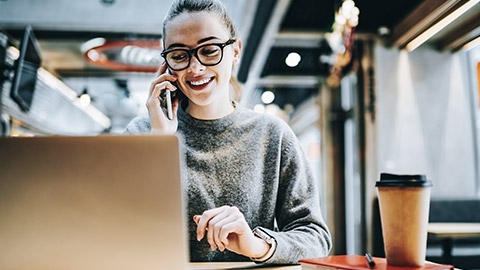 woman talking on the phone while looking at her computer