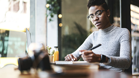 Woman on computer while taking notes