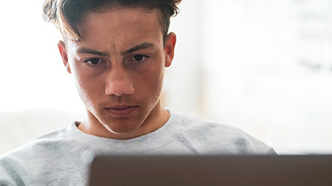 Close view of a teenage gamer reflecting with a serious face