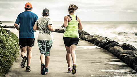 A diverse group running by the coastline