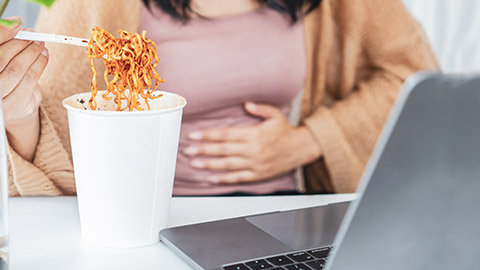 A close view of a person eating noodles and getting a stomach ache