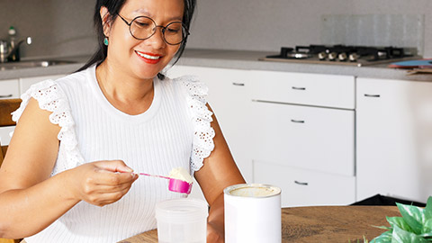 A person making a supplement drink in a kitchen