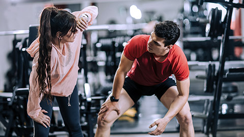 Woman fitness trainer training a man at gym