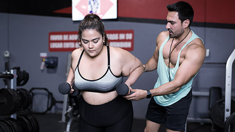 Overweight woman guided by fitness trainor