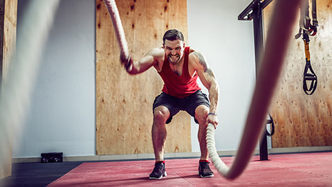 A person in a gym using battle ropes