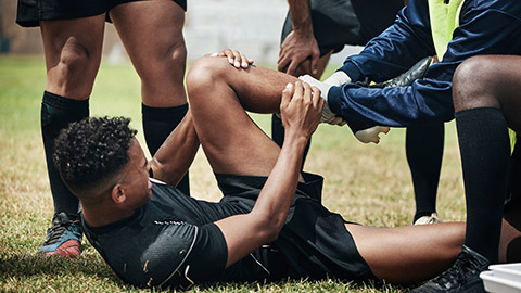 A rugby player laying on the ground with an ankle injury