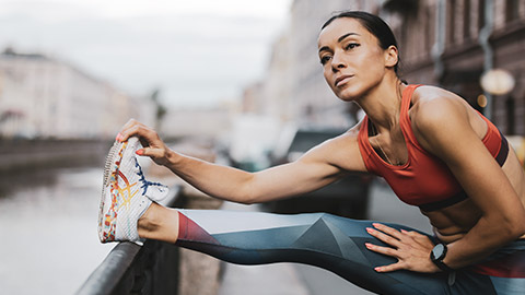 A runner warming up before a run through a city