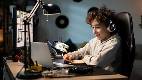 A child designs a building for tech class, does homework, draws with a pencil in a notebook