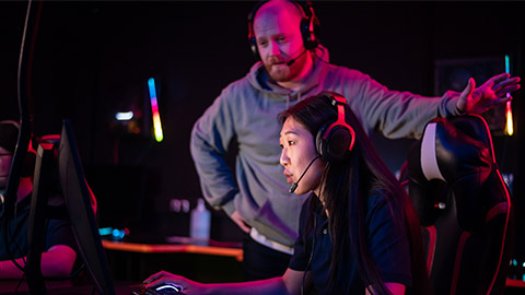 Esports team training camp in computer club with coach, caucasian guy and asian girl