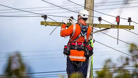 A worker fixing a wooden power pole