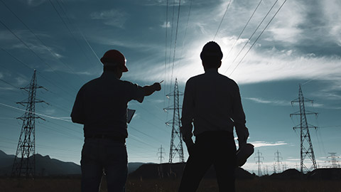 2 workers standing near high voltage power lines