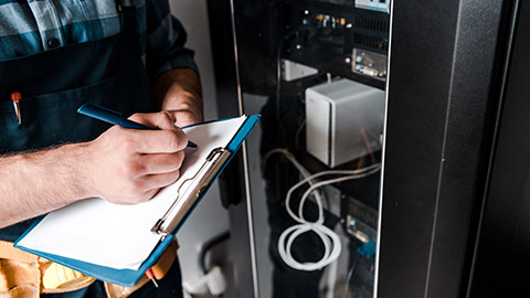 A close view of an electrician writing on a clipboard