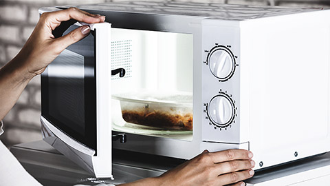 A person opening a microwave oven