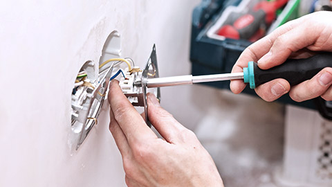 Close-up of hand screwing an electrical outlet