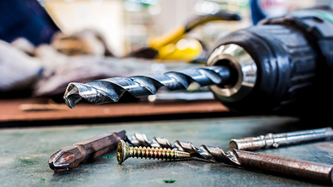 A close view of a drill and drill bits on a workbench