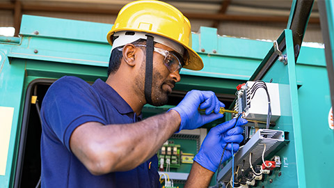 young electrical engineer with protective workware repairing or connecting wires