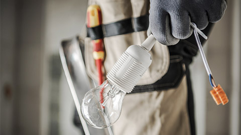 Electric Worker with Bulb in His Hand Preparing For a Light Point Installation. Close Up Photo. Industrial Concept.