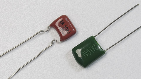 Red and green mylar capacitors on white background isolated. Closeup macro shots.