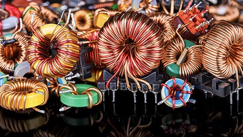 Closeup of colored inductors and transformers with reflection on black background.