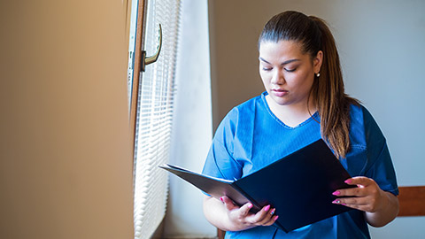 A nurse reading information in a folder in a care facility