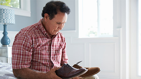 Senior Hispanic Man Suffering With Dementia Trying To Dress