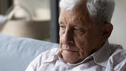 Head shot close up lost in negative thoughts unhappy old senior hoary retired man sitting on couch