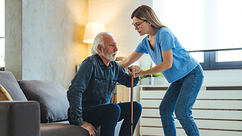 Young caring nurse helping senior old elderly man grandfather walk