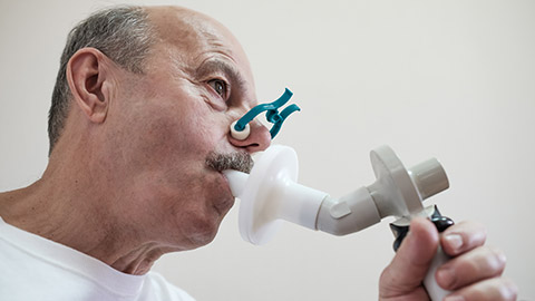 A person blowing in to medical apparatus