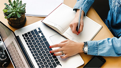 stylish young hipster girl working economist financial analytics holding pen on craft background with laptop and papers