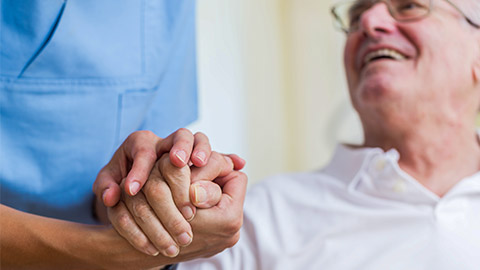 Nurse holding hand of senior man in rest home