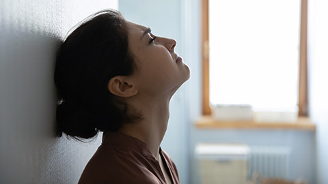 Tired stressed indian woman sit leaning against white wall