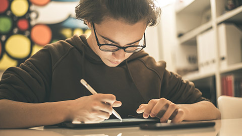 A teenager drawing on a tablet device