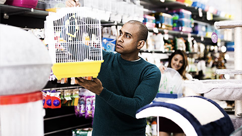 Positive man buying bird cage at pet store