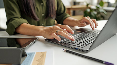 Hand of young female teacher or student typing on laptop keyboard while sitting by desk