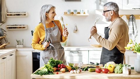 happy couple dancing while preparing healthy meal