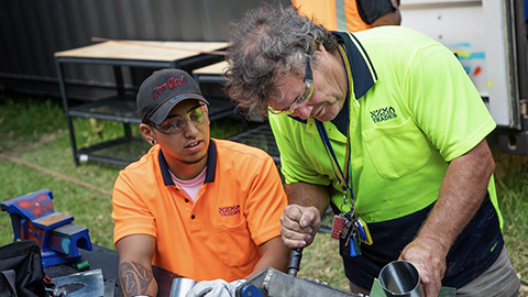 A tradie showing skills to an apprentice