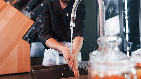 A chef washing hands in a kitchen