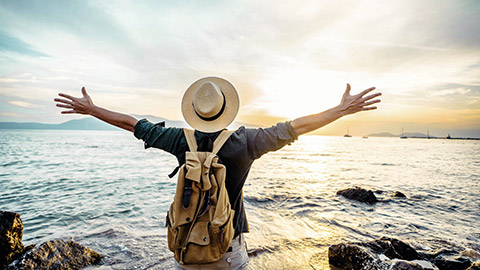 A person stretching their arms out toward the ocean