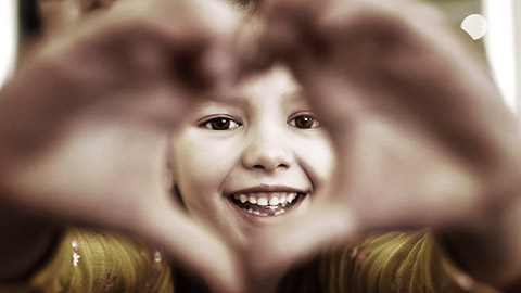 A child making a heart shape with hands