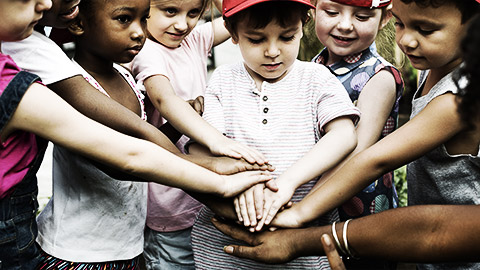 A group of children hands on top of each other showing teamwork and socialization