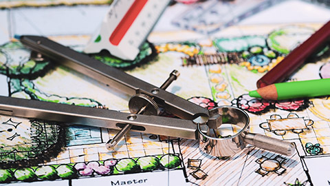 A landscape drawing on a table with pencils, ruler and compass