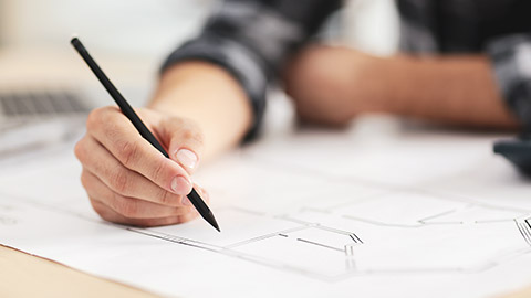 A person drawing a plan with a pencil