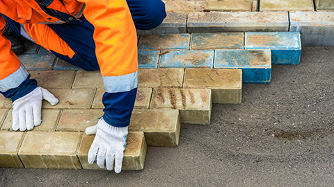 A person laying pavers in a backyard