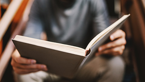 Close up of caucasian man sitting on stairs and reading interesting book