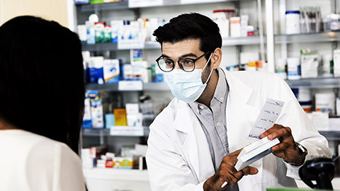 Middle eastern male pharmacist wearing protective hygienic mask to prevent infection selling medications