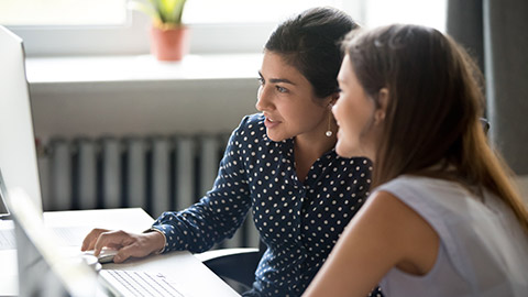 2 people talking and looking at a computer