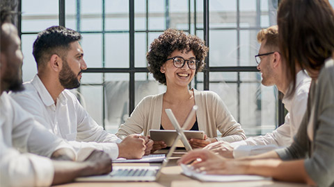 Employees working at computer together, discussing content