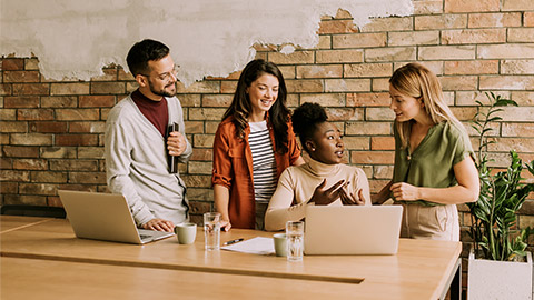 Young multiethnic startup team working by the brick wall in industrial style office