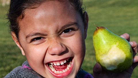 A young girl holding a pear