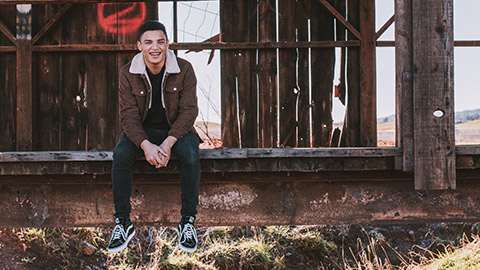 A young pacific islander sitting on a bridge in a rural setting